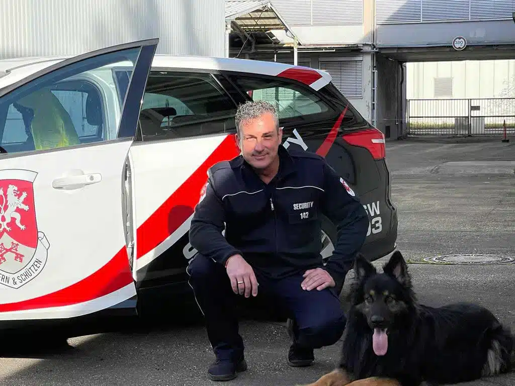 Wachmann mit Dienstfahrzeug und Wachhund